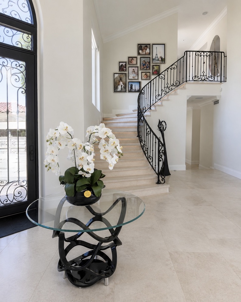 Pelican Ridge, Newport Coast entry with a curved staircase, wrought-iron railing, and white orchids